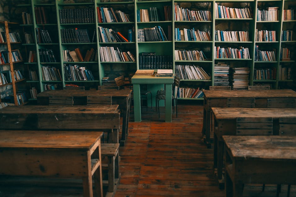 A nostalgic view of an old classroom with wooden desks and bookshelves filled with books.